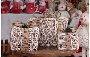 Detailed view of three white woven Christmas gift boxes with burlap bows and festive text.