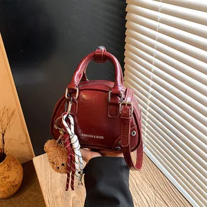 Detailed view of a vintage red mini bowling bag with a cute plush bear keychain detail