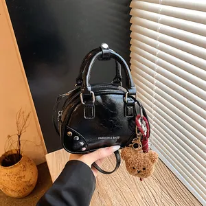 Chic black glossy bowling bag with rivet details and a cute brown plush bear bag charm
