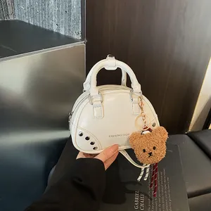 Close-up detail of a white glossy bowling handbag featuring a cute fluffy teddy bear charm