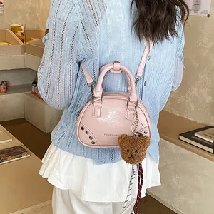 Pink fashion bowling bag with a cute bear keychain shown being worn as crossbody