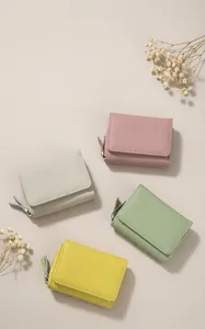 Vraufsicht auf vier bunte dreifach faltbare Ledergeldbörsen auf einem Holztablett.
