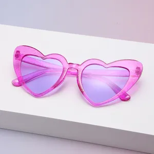 Nahaufnahme einer pinkfarbenen Herzsonnenbrille mit Glitzer und lila Gläsern im Display