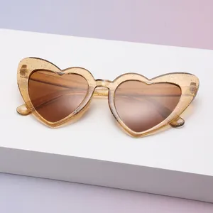 Detailansicht der trendigen herzförmigen Sonnenbrille mit goldenem Glitzerrahmen.