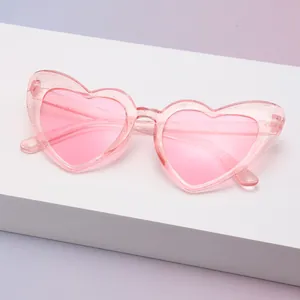 Detailansicht der rosafarbenen herzförmigen Glitzer-Kristall-Sonnenbrille auf weißem Sockel.
