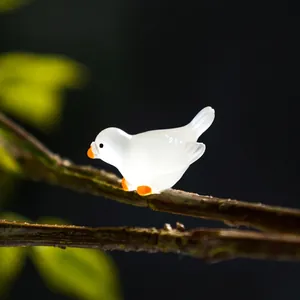Leuchtende Miniatur-Taubenfigur in Weiß auf einem Ast für die Mikro-Landschaft