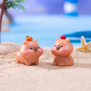 Deux figurines de capybara miniatures mignonnes avec des fruits sur le sable pour paysage DIY.