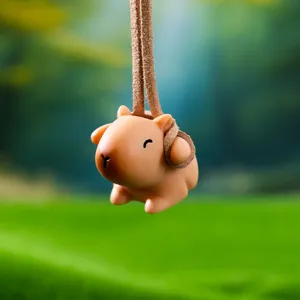 Close-up of a cute swinging Capybara figurine with a brown cord for car or tank decor