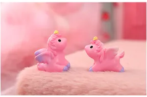 Close-up of miniature pink resin unicorn figurines on a soft pink fluffy background.