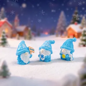 Set di tre graziose statuine di gnomi invernali blu in una scena di villaggio innevato