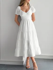 Robe midi blanche élégante à manches bouffantes et jupe à volants dans un cadre très épuré