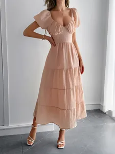 Détail d'une robe maxi rose pêche à volants, manches bouffantes et texture gaufrée