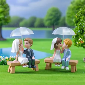 Cute miniature wedding couple figurines kissing under a translucent umbrella on a bench