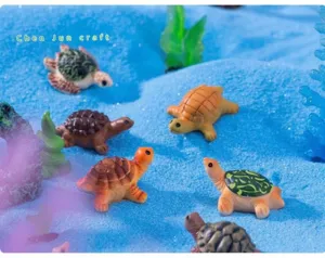 Macro view of colorful miniature sea turtle figurines on blue sand for aquarium decor