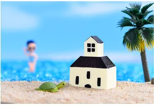 Close-up van een miniatuur mediterrane witte kerk met een kleine schildpad op zand