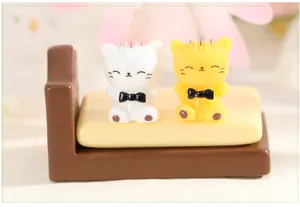 Detailed view of two cute resin cat figurines in white and yellow on a miniature bed