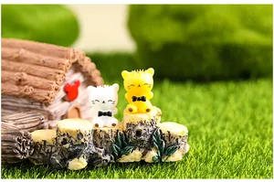 Close-up of two miniature cat figurines sitting on a decorative log for moss micro-landscape
