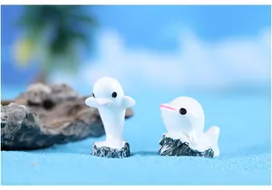 Gedetailleerde weergave van twee mini-hars dolfijnfiguren in een micro strandlandschap