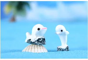 Gedetailleerde close-up van miniatuur witte dolfijnbeeldjes van hars voor microlandschap