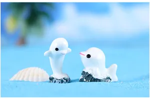 Gedetailleerd zicht op twee miniatuur hars dolfijn figuren in een strand micro landschap.