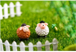 Primo piano di figurine di pecore in miniatura marroni e bianche su erba sintetica verde.