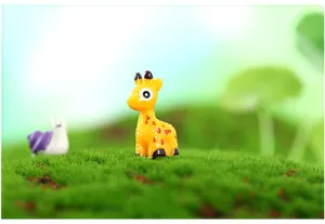 Close-up of a small resin giraffe figurine on green moss for DIY micro landscapes