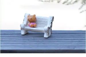 Detailed macro view of a miniature white resin bench ornament with a cute cat figurine