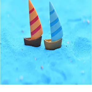 Vue macro détaillée de deux voiliers miniatures de style méditerranéen sur du sable décoratif bleu