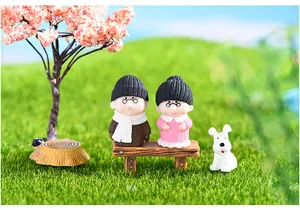 Scena in miniatura con statuine di una coppia di anziani seduti su una panchina in giardino