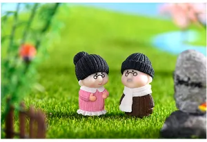 Dettaglio ravvicinato di figurine di nonni in miniatura in abiti invernali su muschio.