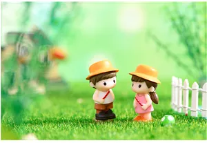Vue détaillée de figurines miniatures de couple avec chapeaux jaunes sur gazon artificiel