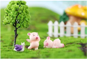 Close-up of cute pink resin pig figurines in a lush green miniature garden mossy landscape