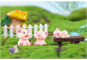 Close-up of cute pink resin pig figurines in a miniature fairy garden landscape