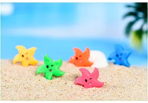 Primo piano di figurine colorate di stelle marine in resina su sabbia fine
