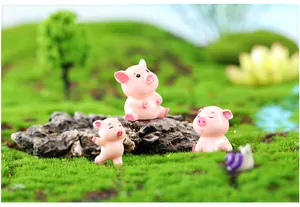 Detailed view of cute pink resin pig figurines in a miniature moss landscape setting