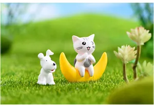 Dettaglio di una simpatica statuina di gatto su una luna gialla in scena di muschio