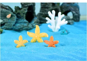 Detailweergave van kleurrijke hars zeester ornamenten in een blauw zand micro landschap aquarium
