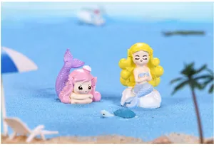 Due adorabili figurine di sirena e una tartaruga su sabbia blu per decorazione