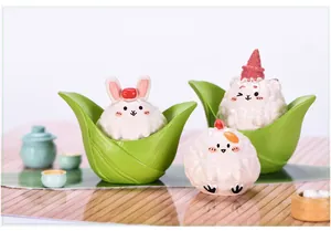 Detailed view of cute Dragon Boat Festival resin figurines in green bamboo leaf base