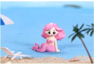 Vista dettagliata di una statuina di sirena rosa su sabbia blu per mini paesaggio