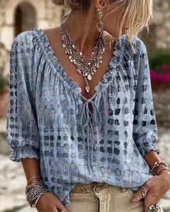 Detalle de una blusa bohemia azul con lunares, escote con volantes y lazo delantero.