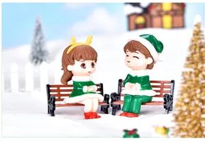 Detailed close-up of cute Christmas couple figurines sitting on benches in snow