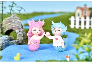 Close-up of cute pink and blue mermaid couple figurines in a miniature river scene