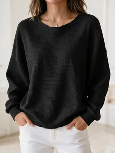 Detailed view of the waffle knit texture on a black oversized crewneck sweatshirt.