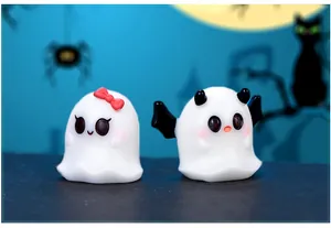 Close-up view of cute mini Halloween ghost figurines with red bow and black bat wings
