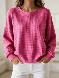 Close-up of pink waffle knit sweatshirt featuring a ribbed crewneck and cuffs.