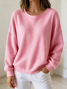 Close-up detail of a pink waffle knit sweatshirt with a classic round neck design