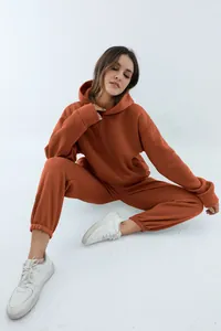 Volledig zicht van een model in een dikke terracotta hoodie en joggingbroek set voor damesmode