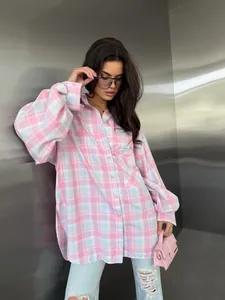 Volledig zicht op een roze geruit oversized overhemd gecombineerd met blauwe jeans