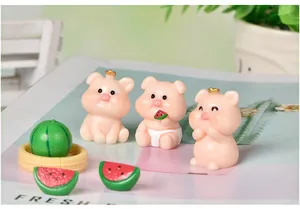 Détail de trois figurines de cochons en résine rose avec mini pastèques pour micro-paysages